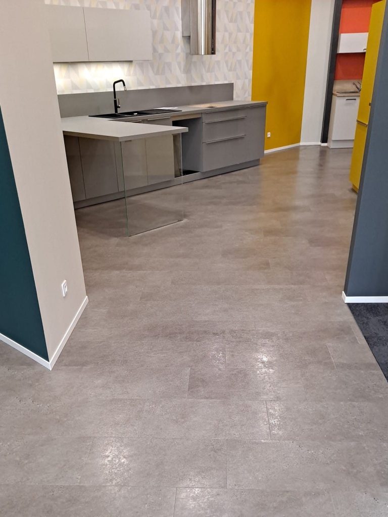 Cuisine moderne avec un sol en béton, murs clairs et accents colorés.