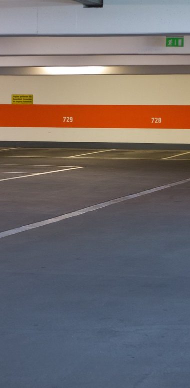 Vue d'un parking vide avec des lignes blanches et un mur orange en arrière-plan.